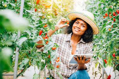 Portrait of young woman standing against plants