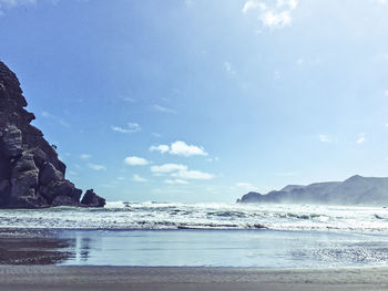 View of calm beach against cloudy sky