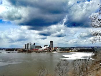 Buildings by river against sky in city