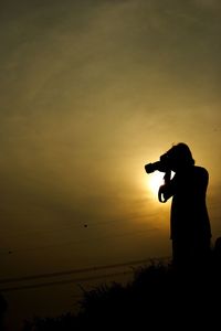 Silhouette man photographing at sunset