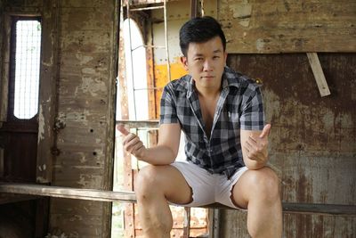 Portrait of man showing thumbs ups while sitting in abandoned room