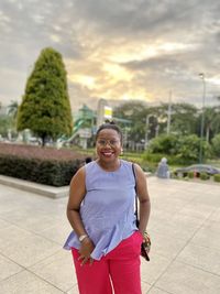 Portrait of smiling woman standing against sky