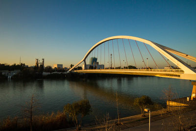 Bridge over river in city against clear sky