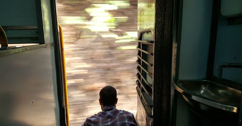 Rear view of man looking through train door
