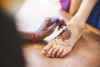Cropped image of woman making heena tattoo on leg