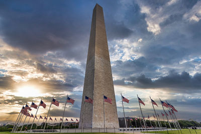 Low angle view of people at monument against sky