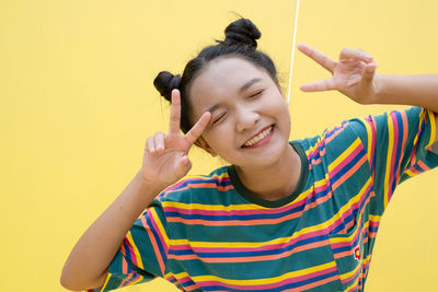 Portrait of smiling young woman against yellow wall