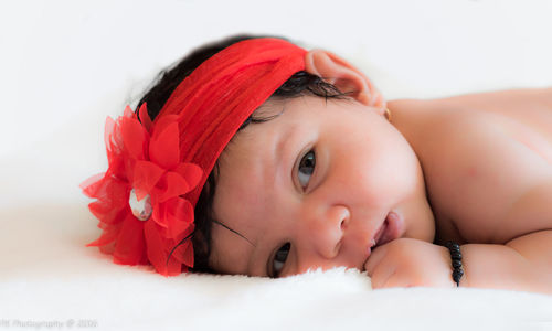 Close-up portrait of baby girl lying on bed
