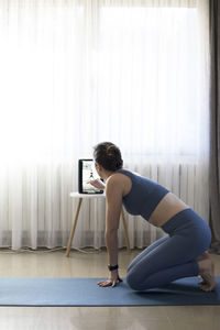 Full length side view of woman standing against curtain