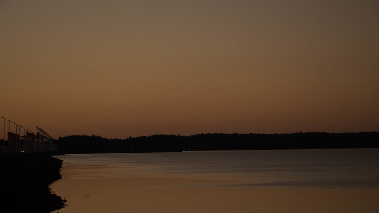 SCENIC VIEW OF RIVER AGAINST CLEAR SKY AT SUNSET