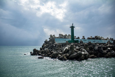 Lighthouse by sea against sky