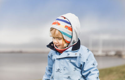 Close-up of girl wearing warm clothes while standing against sky during winter