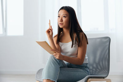 Young woman using mobile phone while sitting on sofa at home