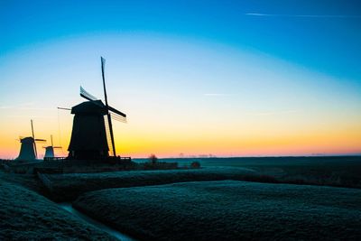 Traditional windmill on field against sky at sunset