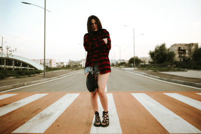 Full length of fashionable young woman on zebra crossing in city