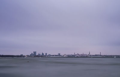 Sea by cityscape against sky