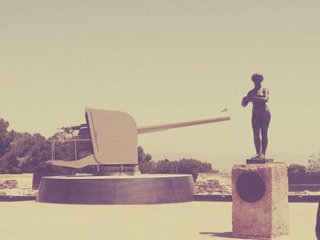 Woman standing by statue against clear sky