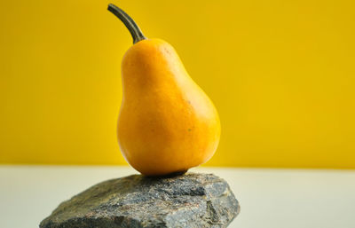 Unusual pumpkin on a stone rock podium with yellow background