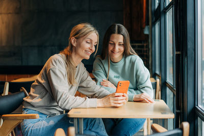 Young woman using mobile phone while sitting at home