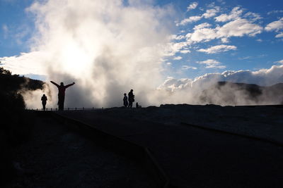 Silhouette people against geyser