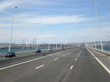 Cars on highway in city against sky