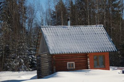 White house on snow covered field against trees in forest