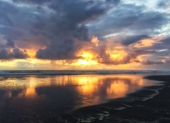 Scenic view of sea against cloudy sky at sunset
