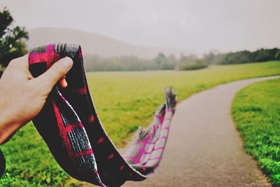 Close-up of hand holding umbrella on field