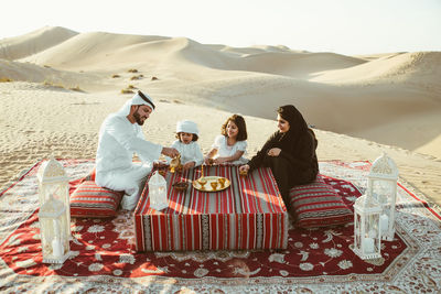 High angle view of family having tea on carpet at desert