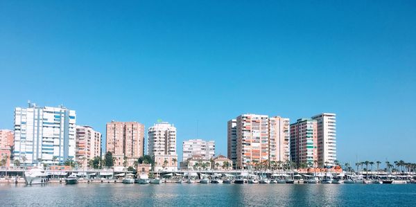 Sea by buildings against clear blue sky