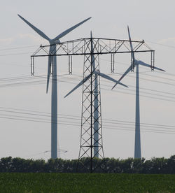 Low angle view of wind turbines on field against sky