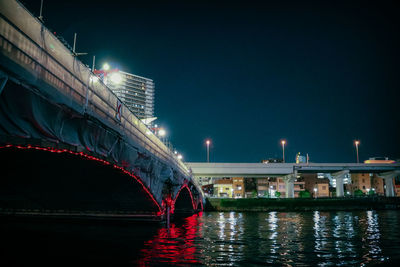 Illuminated bridge over river against sky at night