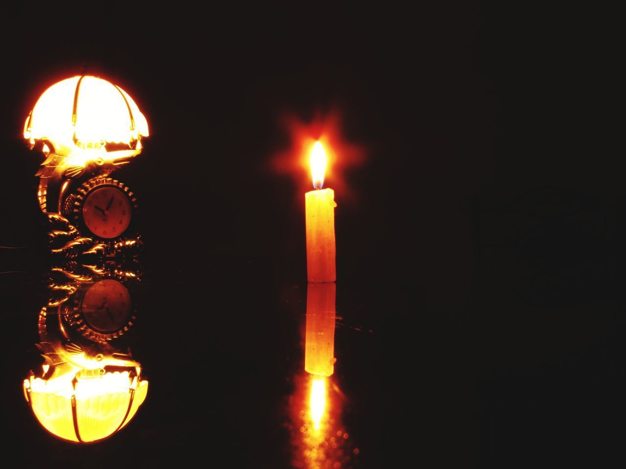 CLOSE-UP OF LIT CANDLES IN DARK