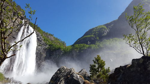 Low angle view of waterfall against clear sky