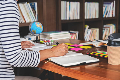Midsection of man reading book on table