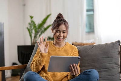 Young woman using laptop while sitting on sofa at home