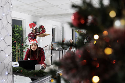 Rear view of woman standing against illuminated christmas tree