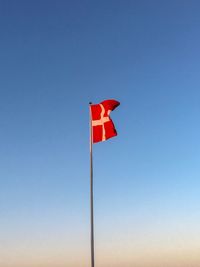 Low angle view of flag against clear blue sky