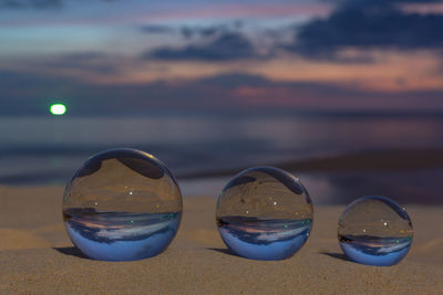 Close-up of sunglasses at beach against sky during sunset