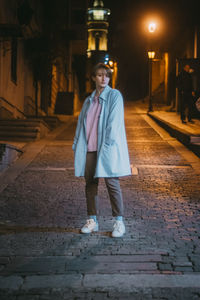 Portrait of man standing on footpath at night