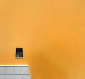 Low angle view of window on orange wall