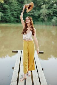 Portrait of young woman with arms outstretched standing on footbridge