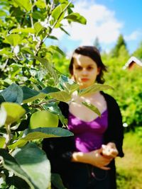 Woman holding plant while standing outdoors