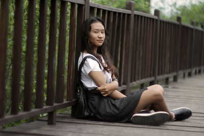 Young woman looking away while sitting on railing