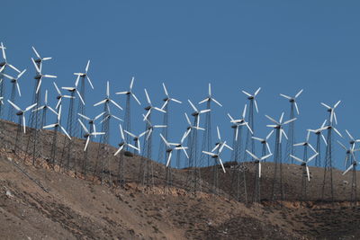 Low angle view of windmills against blue sky