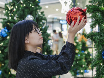 Woman holding red bauble during christmas in shopping mall