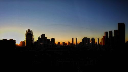 Silhouette buildings against sky during sunset