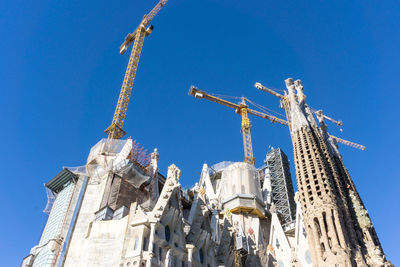 Low angle view of sagrada familia against clear blue sky in city