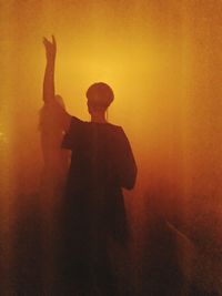 Silhouette man standing against orange sky