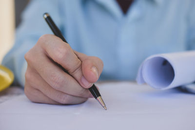 Close-up of man hand holding paper on table